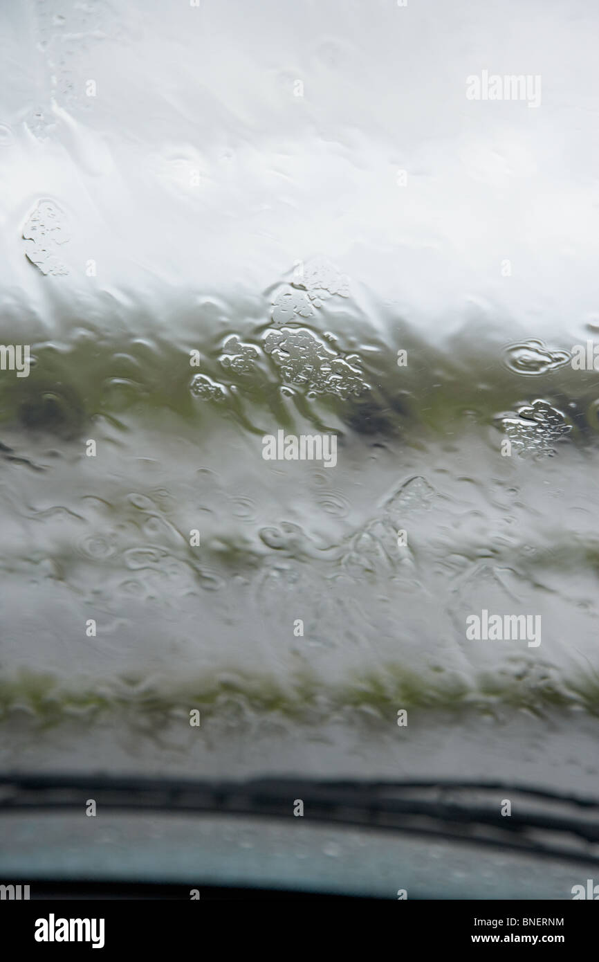 Guardando fuori attraverso il parabrezza auto a pioggia caduta sul vetro durante l'estate in Regno Unito Irlanda Foto Stock