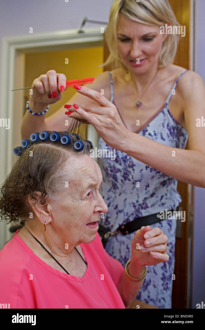 Vecchia età pensionato avente capelli messi in rotoli in una casa di cura, Ipswich, Suffolk, Regno Unito. Foto Stock