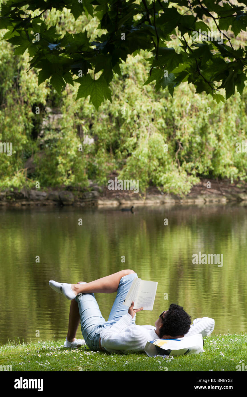 Donna spagnola libro lettura accanto al laghetto di St Stephen's Green park, Dublino, Irlanda Foto Stock