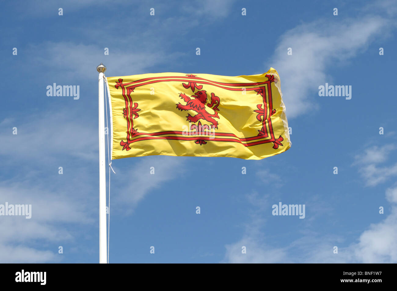 Il giallo e il rosso Scottish leone rampante battenti bandiera contro un cielo azzurro con poche nuvole bianche Foto Stock