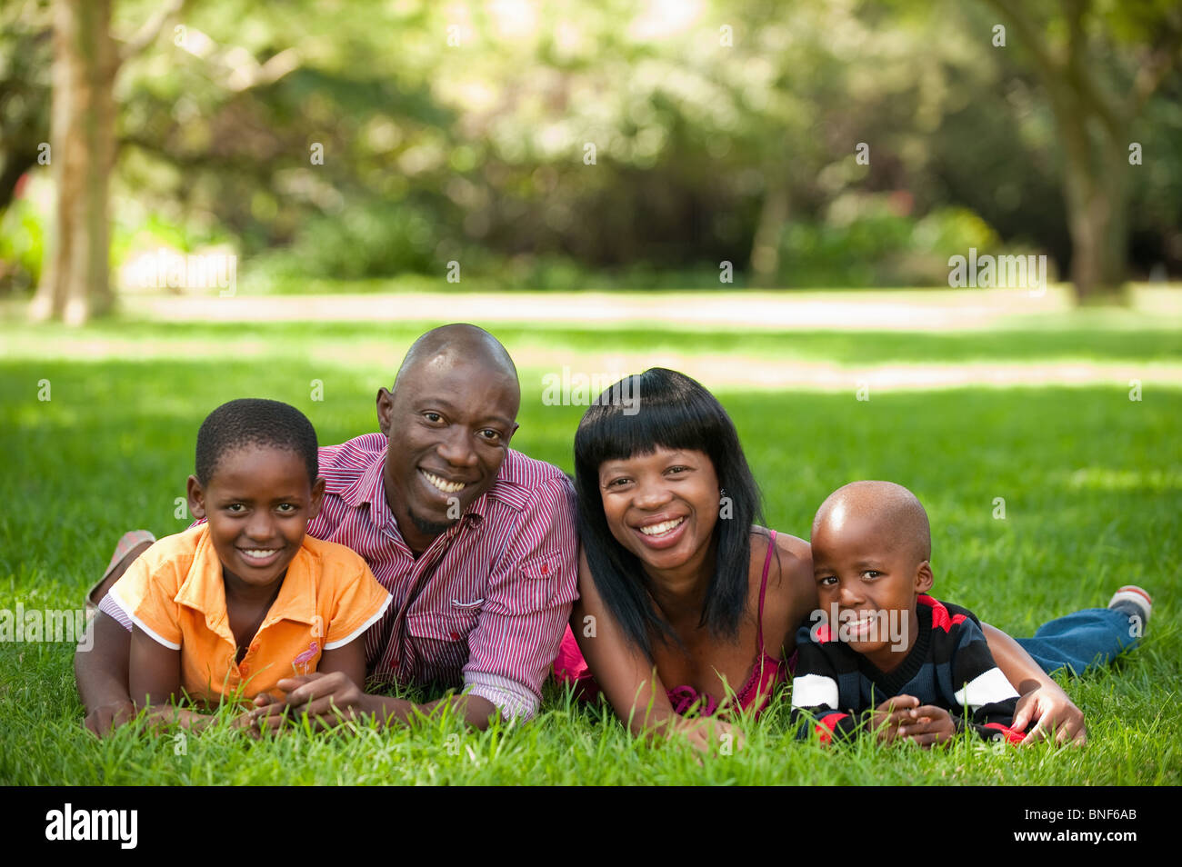 Ritratto di famiglia con bambini (4-8) giacente su erba, Johannesburg, provincia di Gauteng, Sud Africa Foto Stock