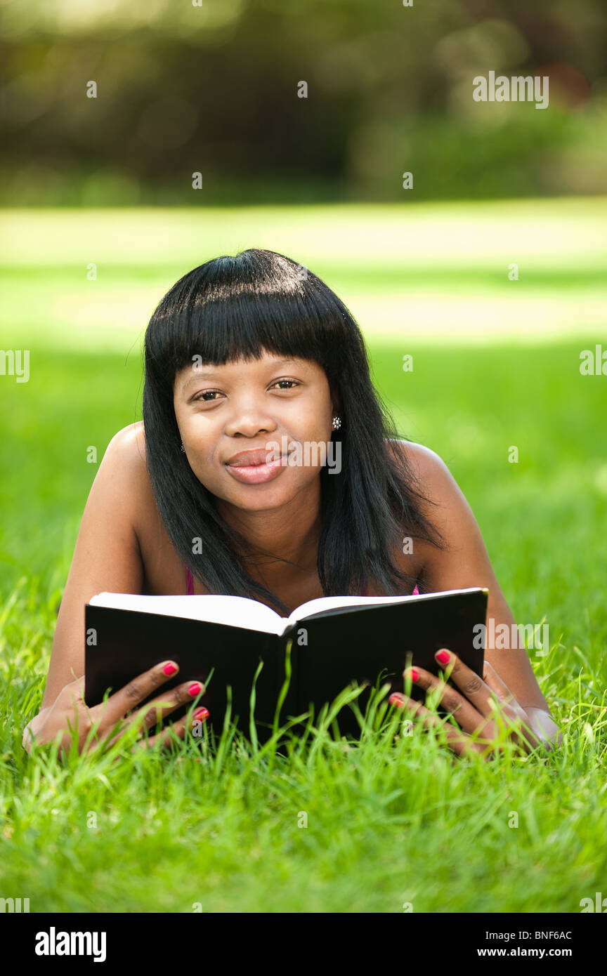 Ritratto di donna lettura sul prato in giardino, Johannesburg, provincia di Gauteng, Sud Africa Foto Stock