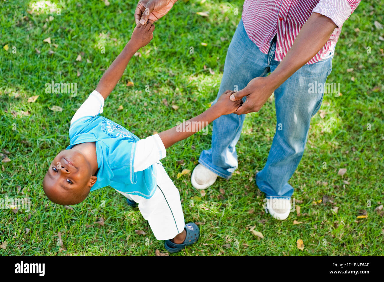 Ragazzo (4-5) giocando con il padre sul prato in giardino, Johannesburg, provincia di Gauteng, Sud Africa Foto Stock