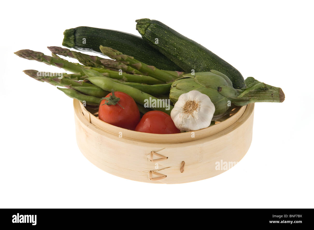 Sistema per la cottura a vapore di bambù con pomodori, asparagi, zucchine, Fagioli baccelli e una testa di aglio. Foto Stock