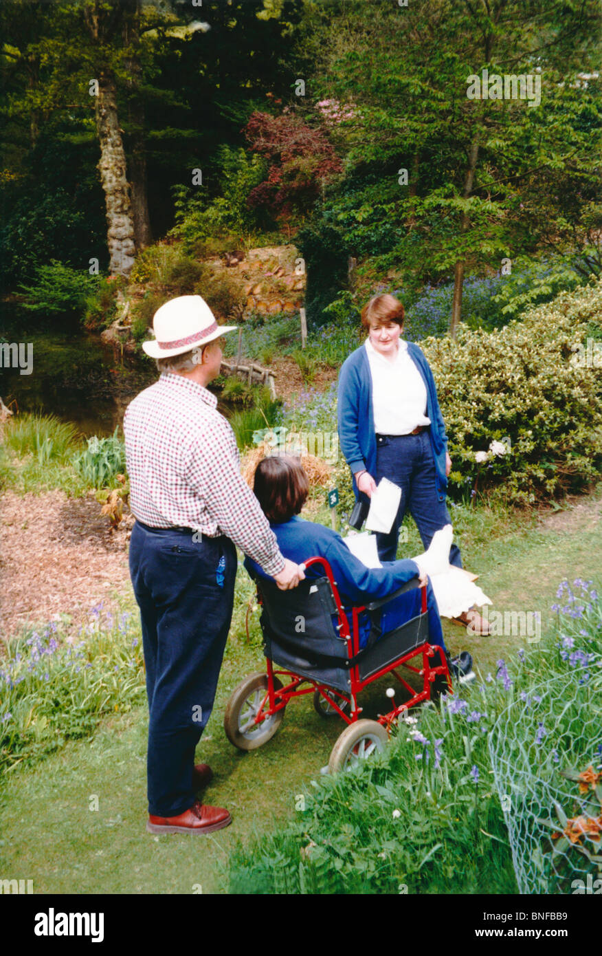 Donna con una colata di gesso sulla sua gamba in una sedia a rotelle la  visita di giardini in Surrey Foto stock - Alamy