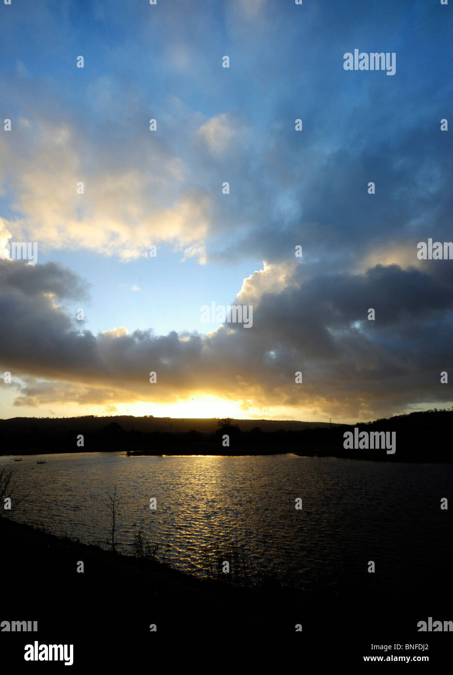 Tramonto su un lago con soffici nuvole e cielo blu Foto Stock