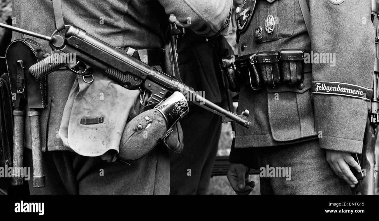 WW2 esercito tedesco soldato con officer che trasportano MP40 9 mm mitragliatore. Re storico la promulgazione. Monocromatico Foto Stock