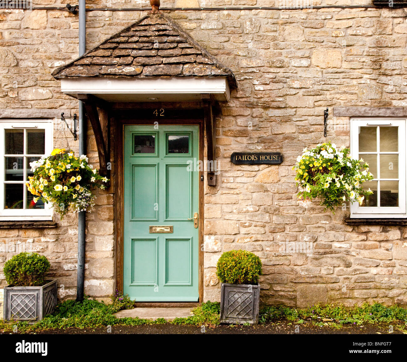 Legno verde porta anteriore di un vecchio Cotswold cottage in pietra nel villaggio di Sherston, Wiltshire, Inghilterra, Regno Unito Foto Stock