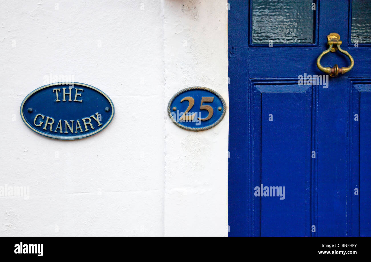 Ghisa house il nome e il numero delle piastre sul muro dipinto di bianco e blu della porta anteriore con ottone respingente Foto Stock