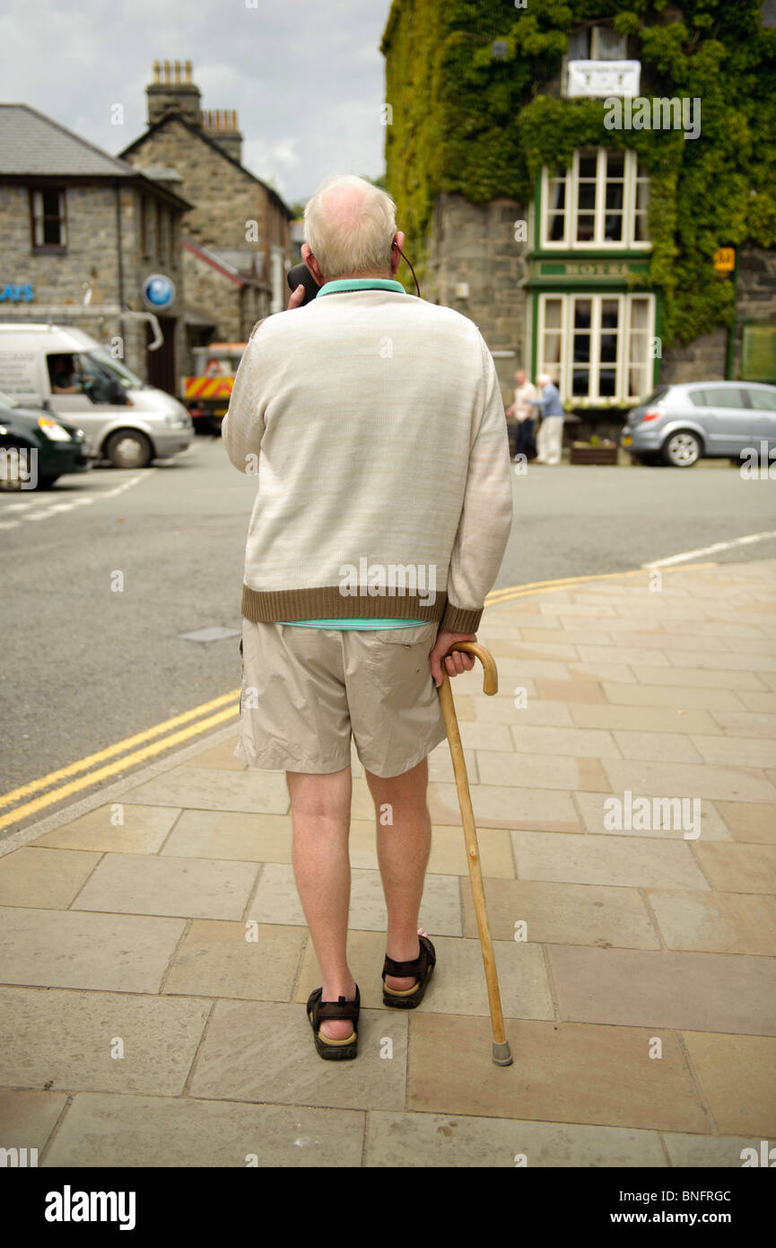 Vista posteriore di un anziano uomo a camminare con l'aiuto di un bastone a Dolgellau, Regno Unito Foto Stock