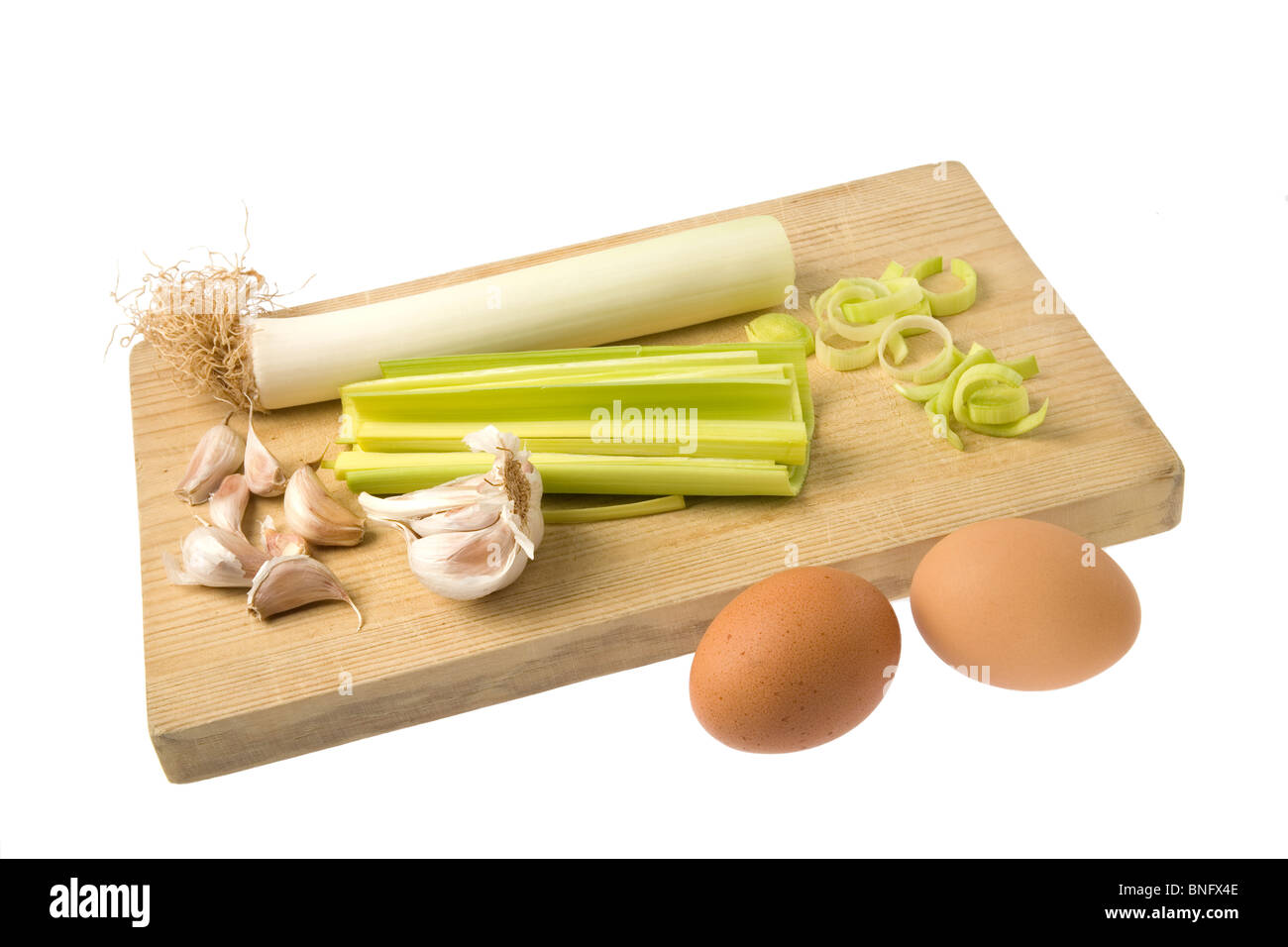 Gruppo di uova, porri e aglio su un tagliere di legno isolata contro uno sfondo bianco. Foto Stock