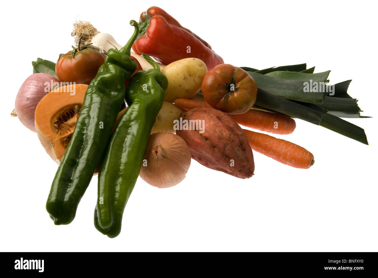 Un gruppo di verde e peperoni rossi, zucca, patate dolci, pomodori, cipolle patate e porri isolata contro il bianco. Foto Stock