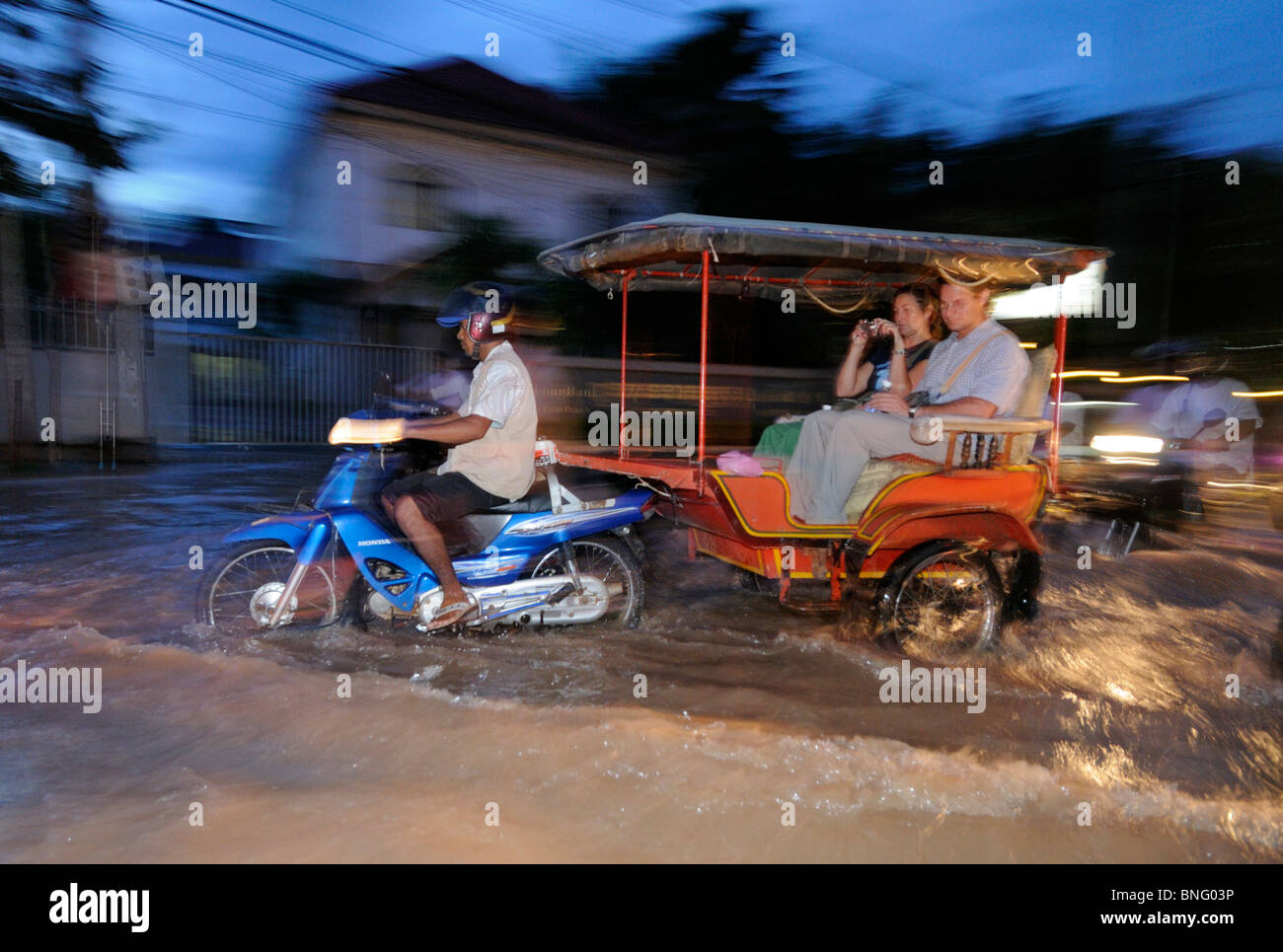 I turisti a cavallo attraverso strade inondate di Siem Reap, Cambogia Foto Stock