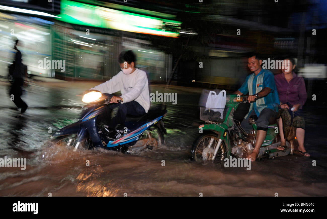 Popolo cambogiano guidare moto in strade inondate di Siem Reap, Cambogia Foto Stock