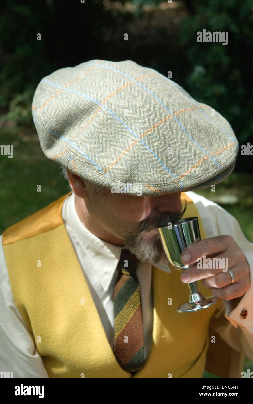 Berretto piatto in tweed moderno, grande ed elegante, uomo che beve con un calice d'argento, gilet, alla moda Londra, Inghilterra, Regno Unito. HOMER SYKES Foto Stock