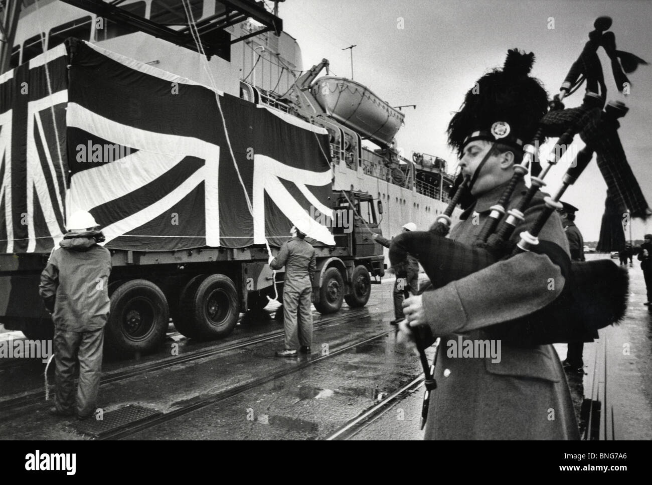 Un militare di piper giocare come un freightliner piena di bare ritorna dalla guerra delle Falkland nel 1982. Foto Stock