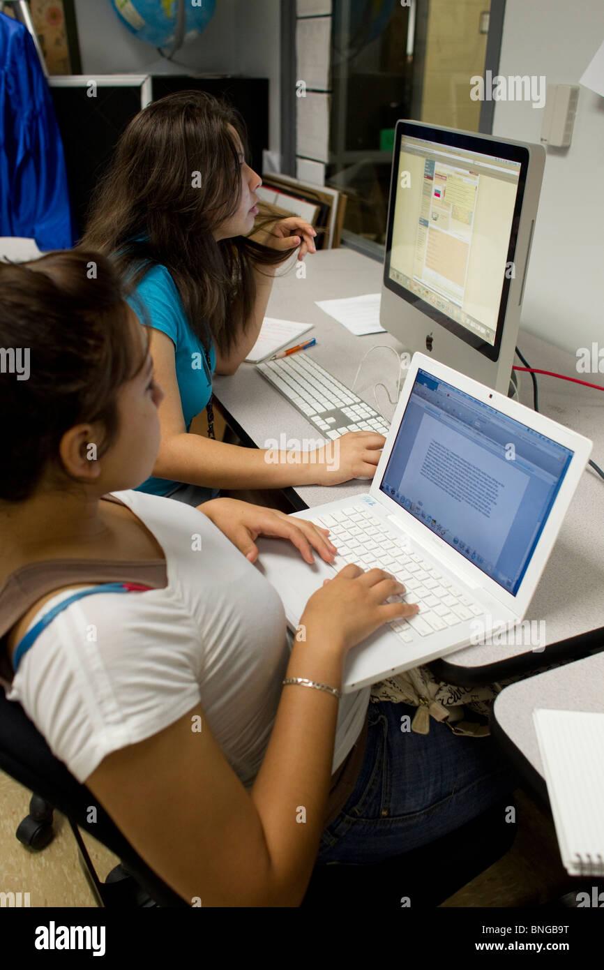 Studentessa sul computer portatile scrive la ricerca carta mentre il compagno di classe utilizza il computer desktop per fare online ricerca in classe Foto Stock