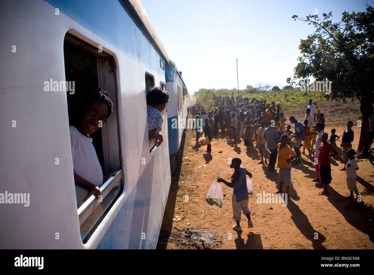 Gli abitanti del villaggio e i fornitori locali di salutare il treno in corrispondenza di una delle sue numerose fermate tra Nampula e di Cuamba, Mozambico. Foto Stock