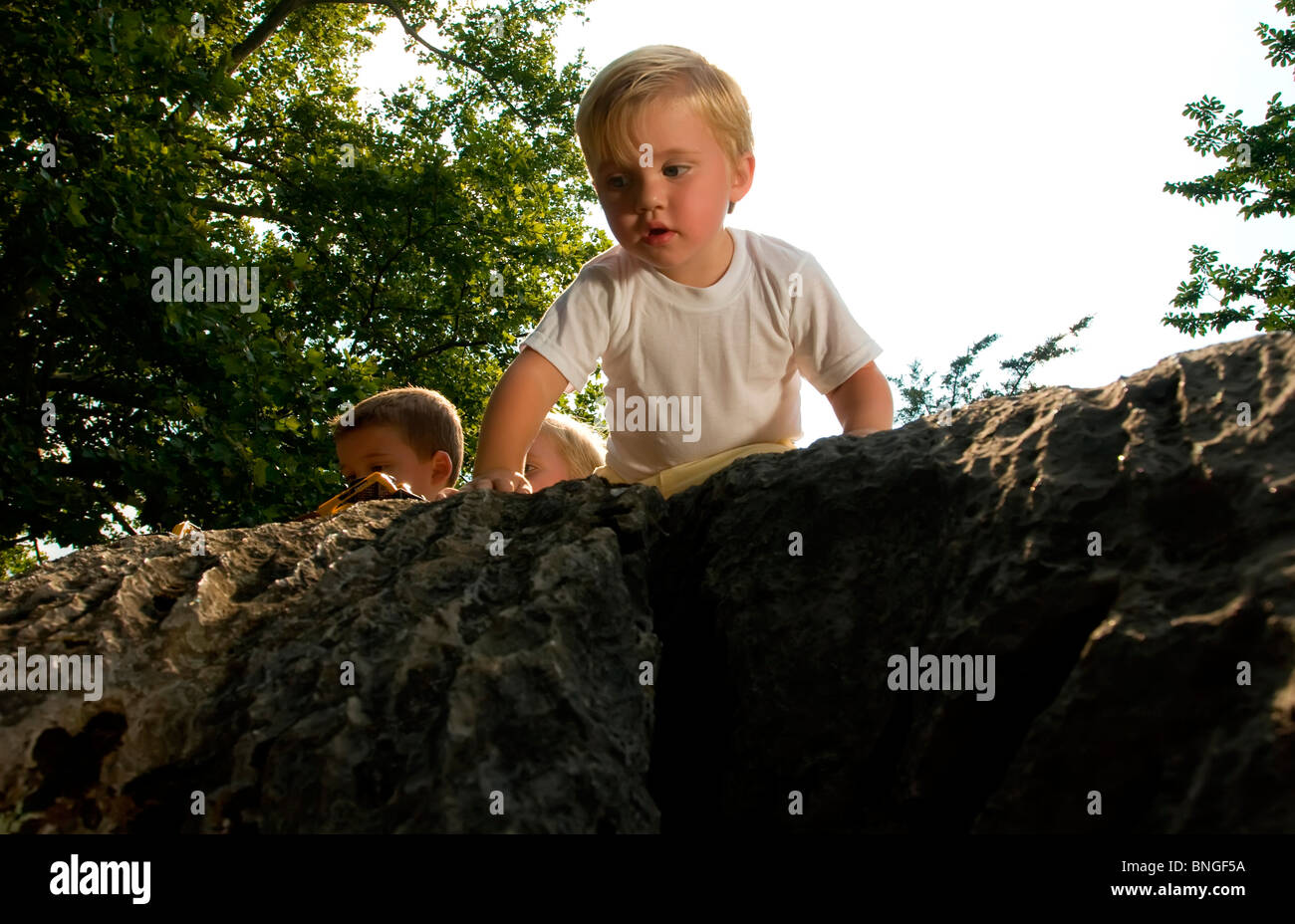 Baby boy guardando in giù da una roccia Foto Stock