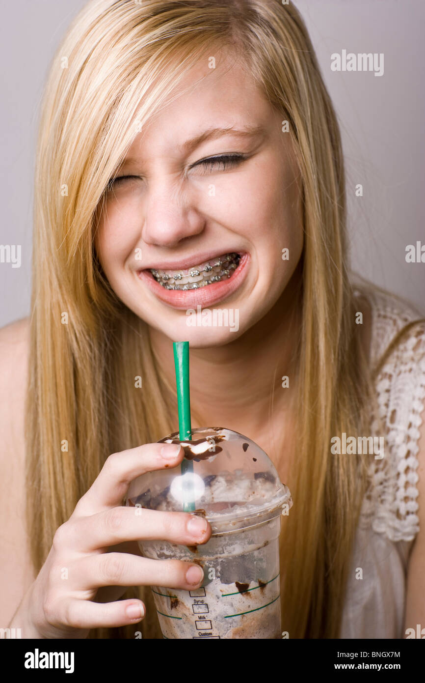 Ragazza adolescente wincing da un cervello freeze mentre si beve caffè ghiacciato Foto Stock