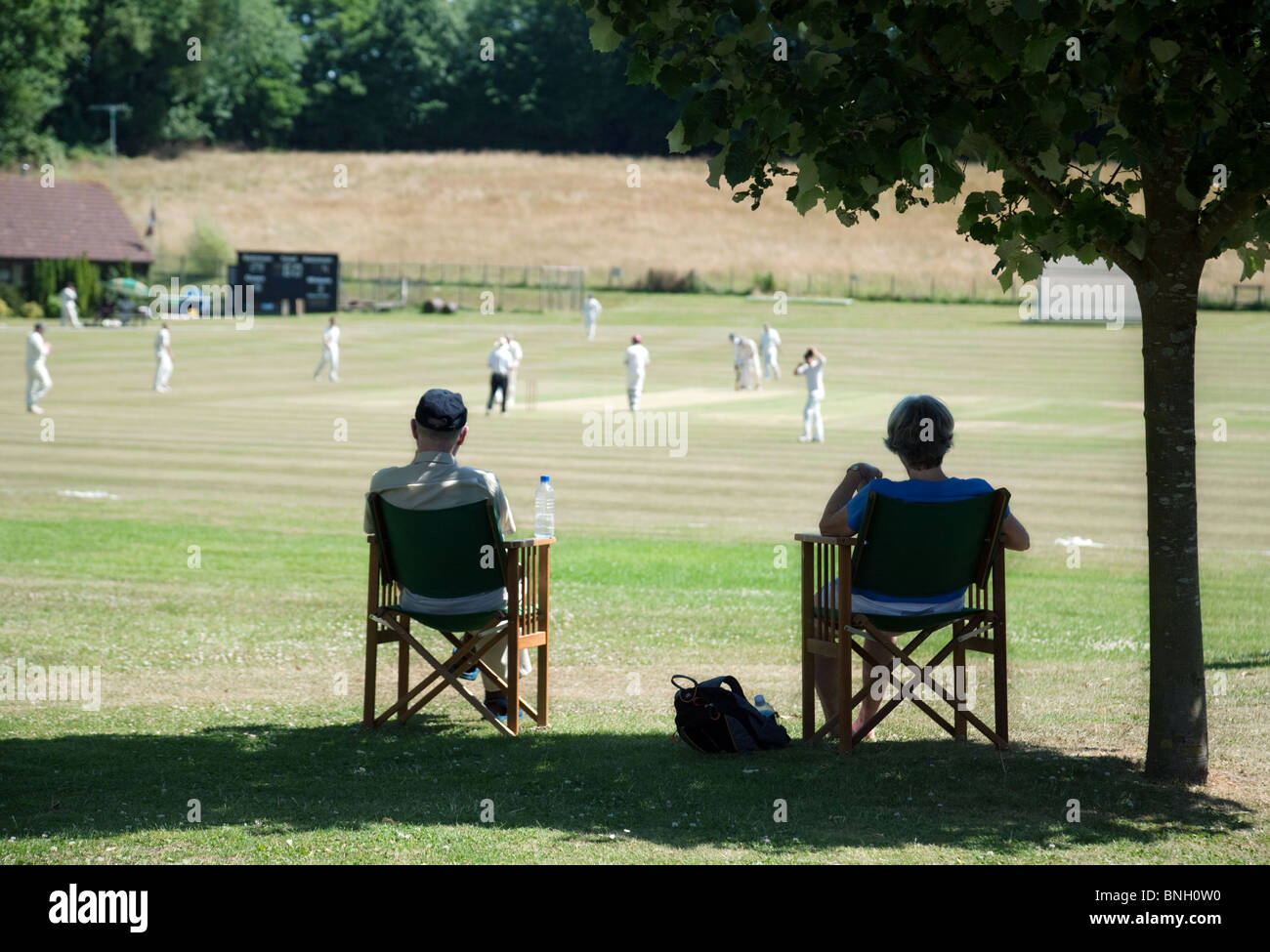 Un paio di guardare una partita di cricket di villaggio in villaggio di Lyminge vicino a Folkestone, Kent, Regno Unito Foto Stock