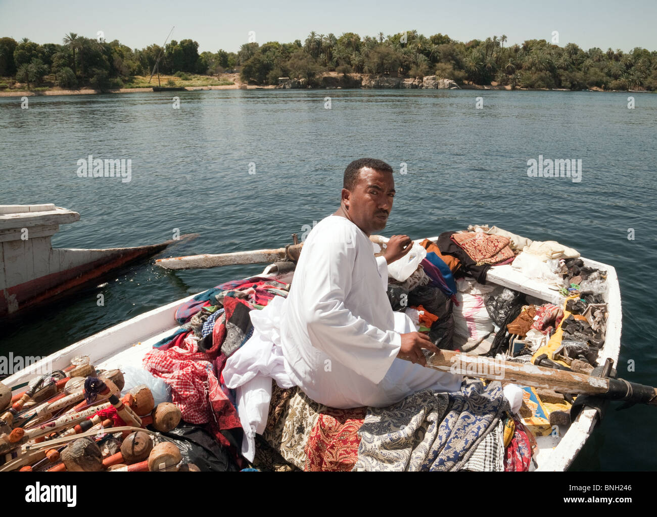 Egitto stile di vita; un commerciante egiziano di mercato con i suoi beni in una barca a remi cercando di vendere ai turisti, il fiume Nilo ad Assuan, Alto Egitto Africa Foto Stock