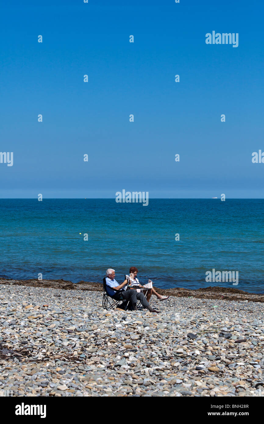 Giovane leggendo i giornali sulla spiaggia deserta in estate a Bray, nei pressi di Dublino, Irlanda Foto Stock