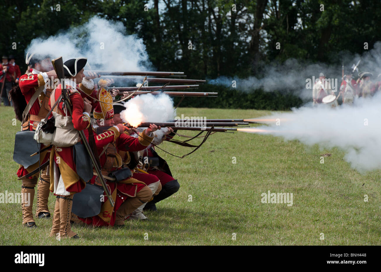 Ottavo Re del reggimento di soldati a piedi sparando flintlock moschetti sul campo di battaglia. La rievocazione Foto Stock