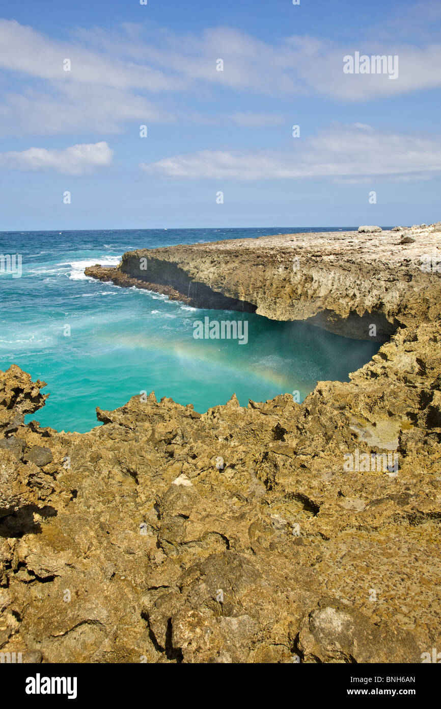 Aspre coste rocciose di Aruba con un arcobaleno contro le profonde acque blu Foto Stock