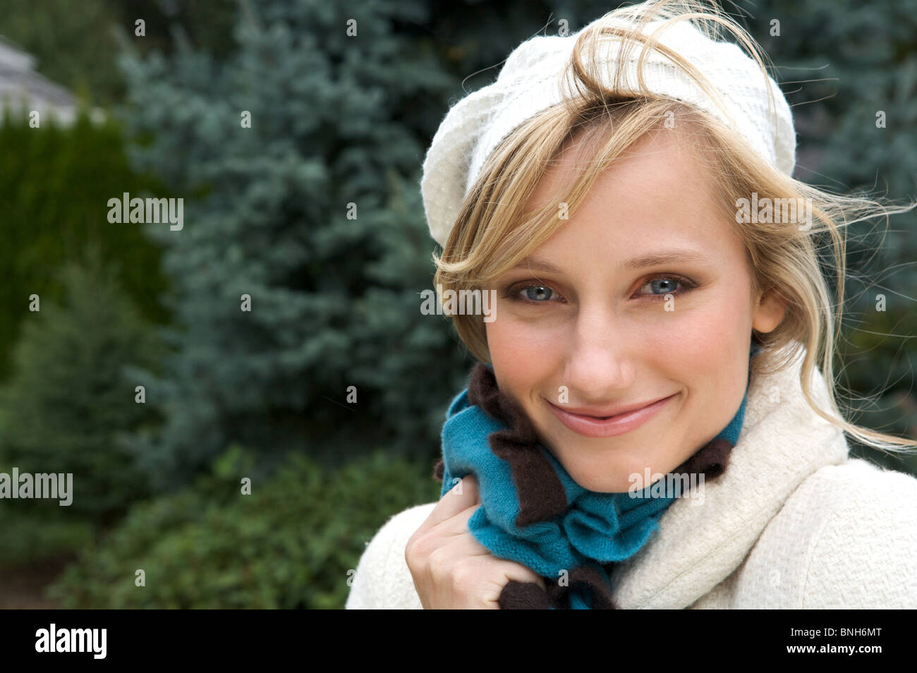 Bella bionda in inverno cappello bianco e rivestire indossando una sciarpa con un sorriso Foto Stock