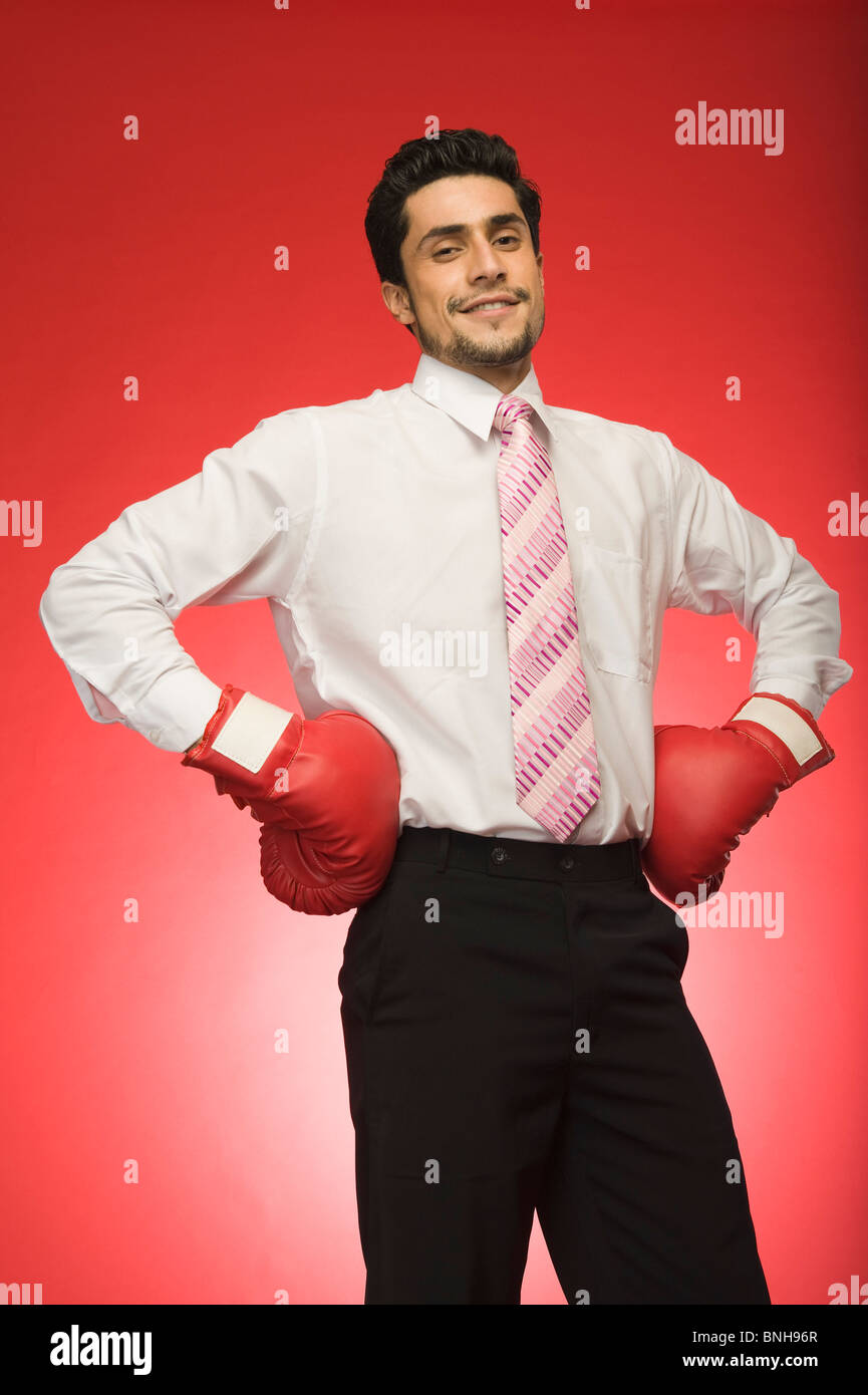 Ritratto di un imprenditore che indossa guantoni da pugilato e in piedi con le braccia akimbo Foto Stock
