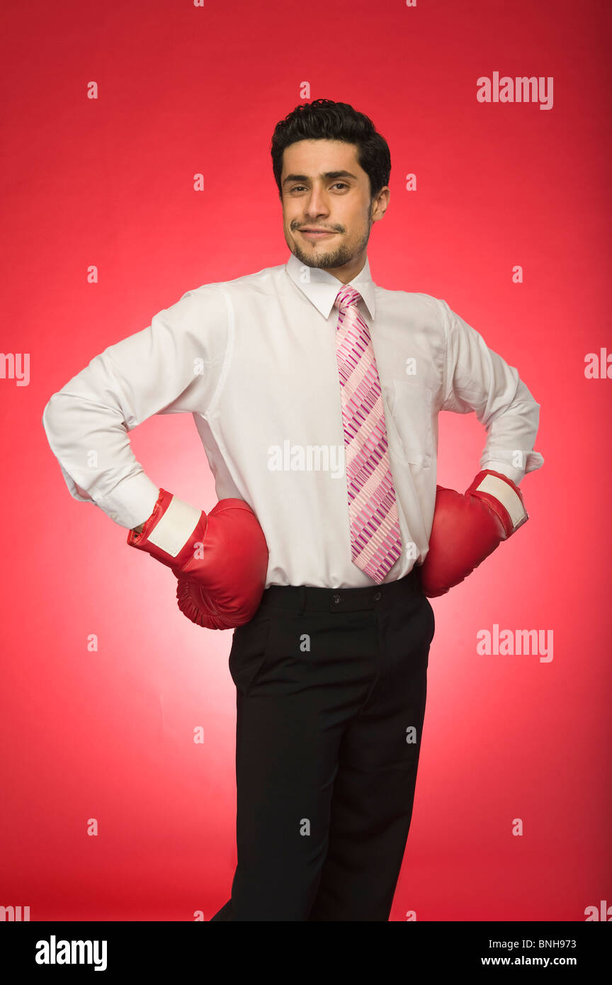 Ritratto di un imprenditore che indossa guantoni da pugilato e in piedi con le braccia akimbo Foto Stock