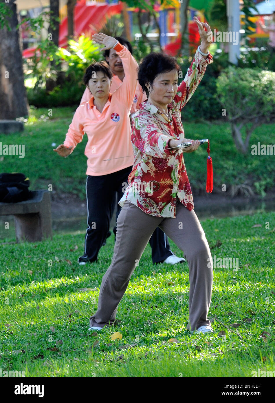 Donna di eseguire il Tai Chi esercita con una grande spada nel Parco Lumpini, Bangkok Foto Stock