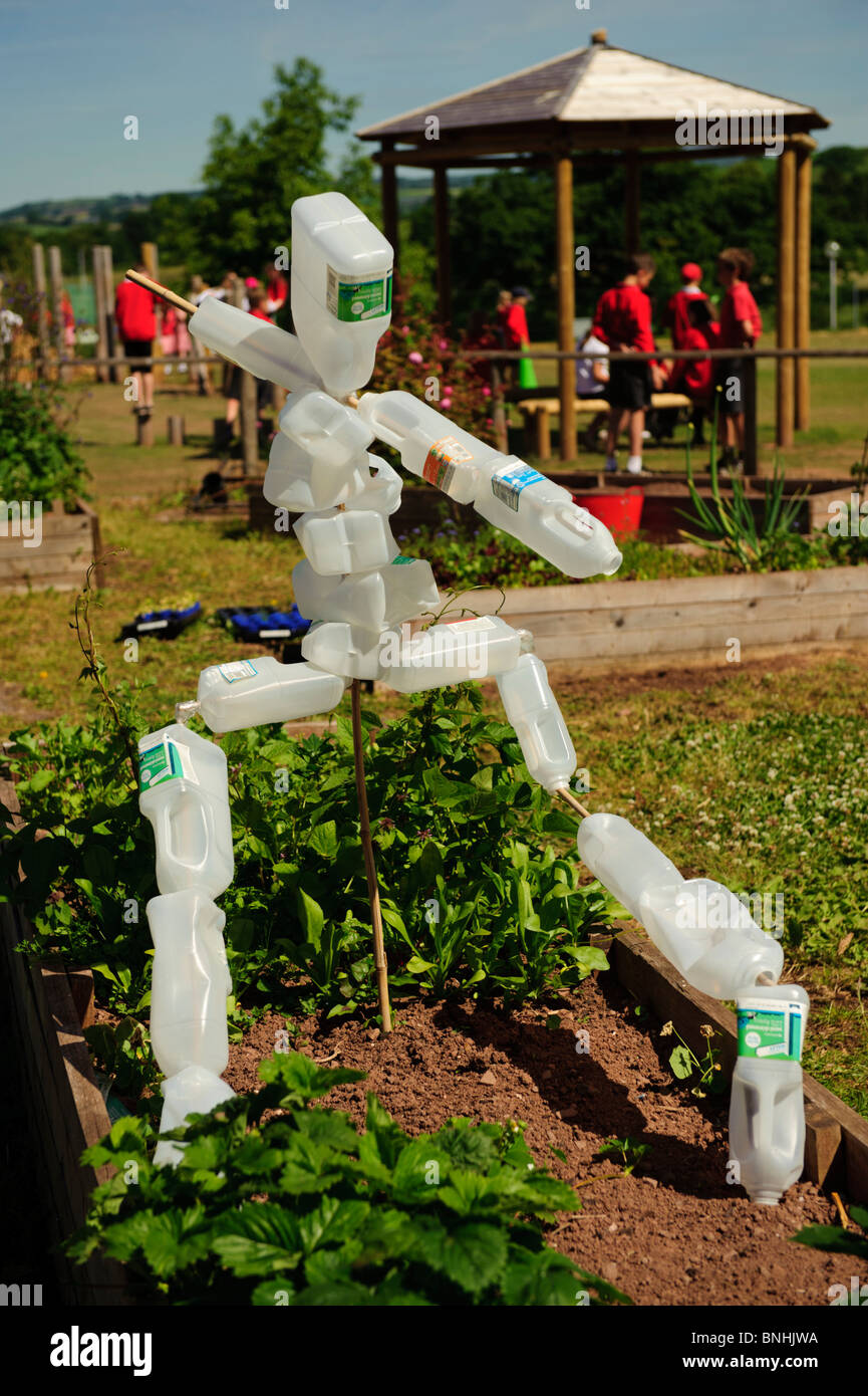 Uno spaventapasseri realizzati con plastica riciclata bottiglie di latte in una scuola primaria giardino, Wales UK Foto Stock