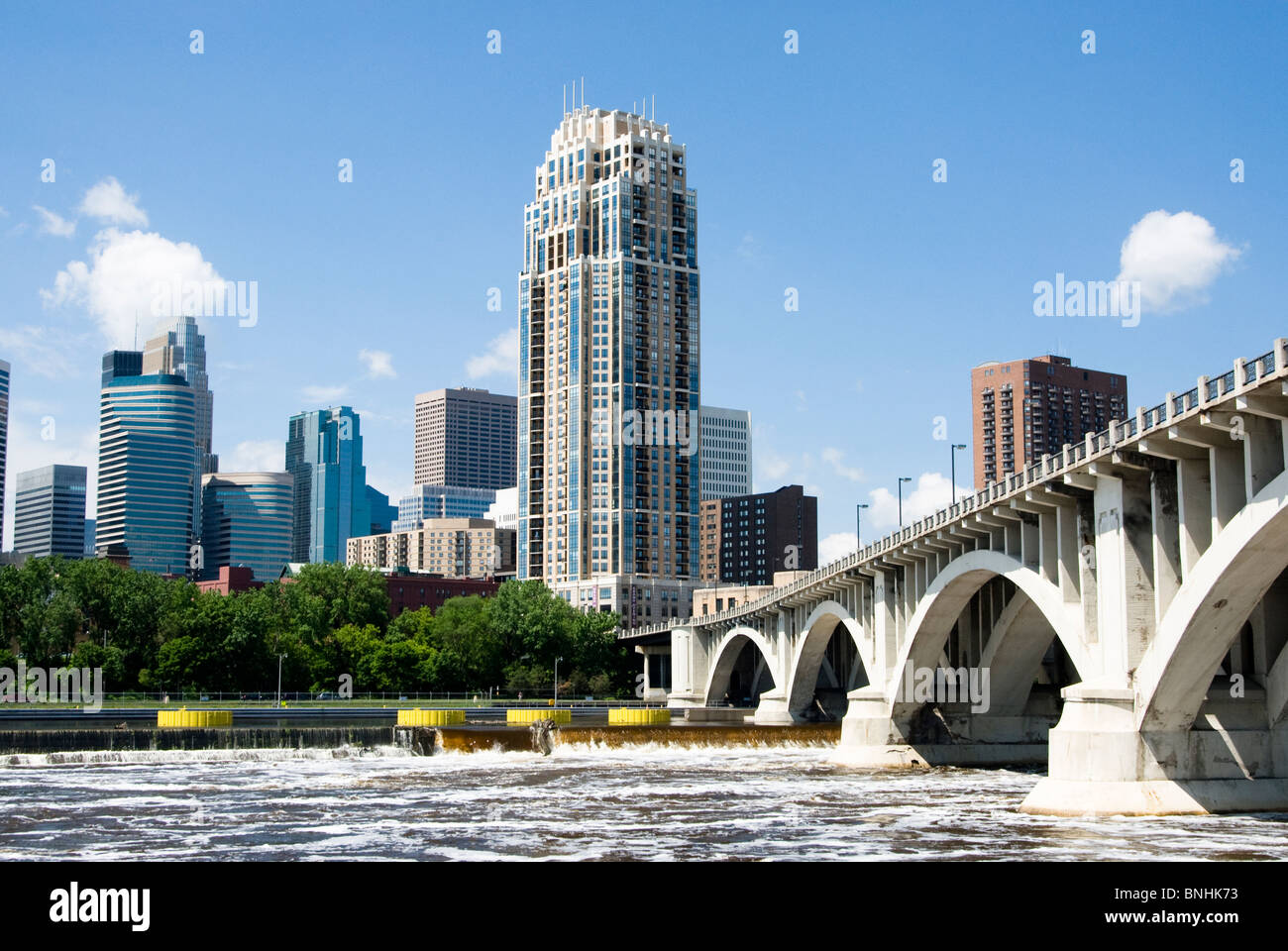 Una vista della skyline di Minneapolis dalla riva a ovest del fiume Mississippi. Il fiume Mississippi è visto in primo piano. Foto Stock