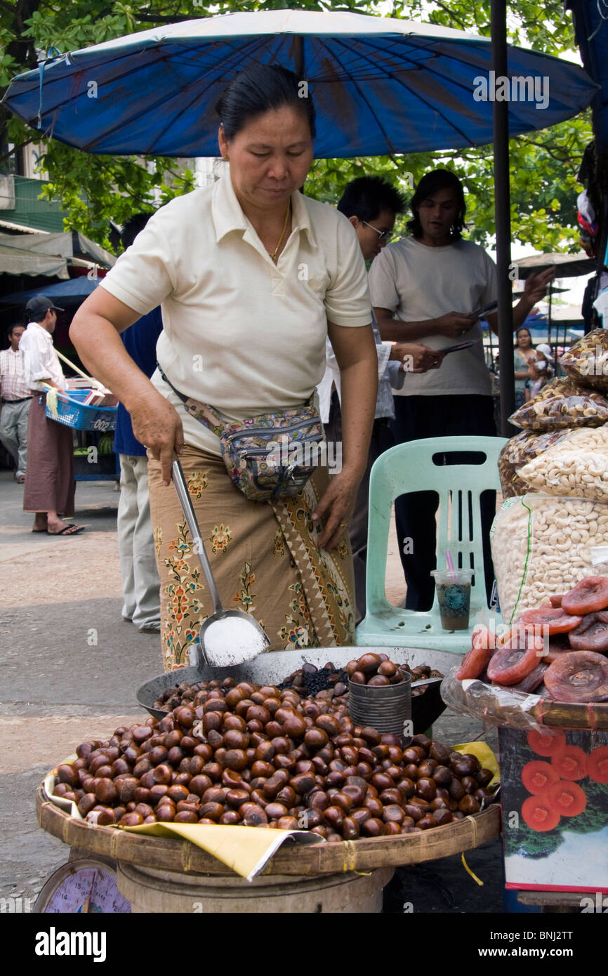 Donna sul mercato nel Myanmar (Birmania) vendita di castagne arrostite Foto Stock