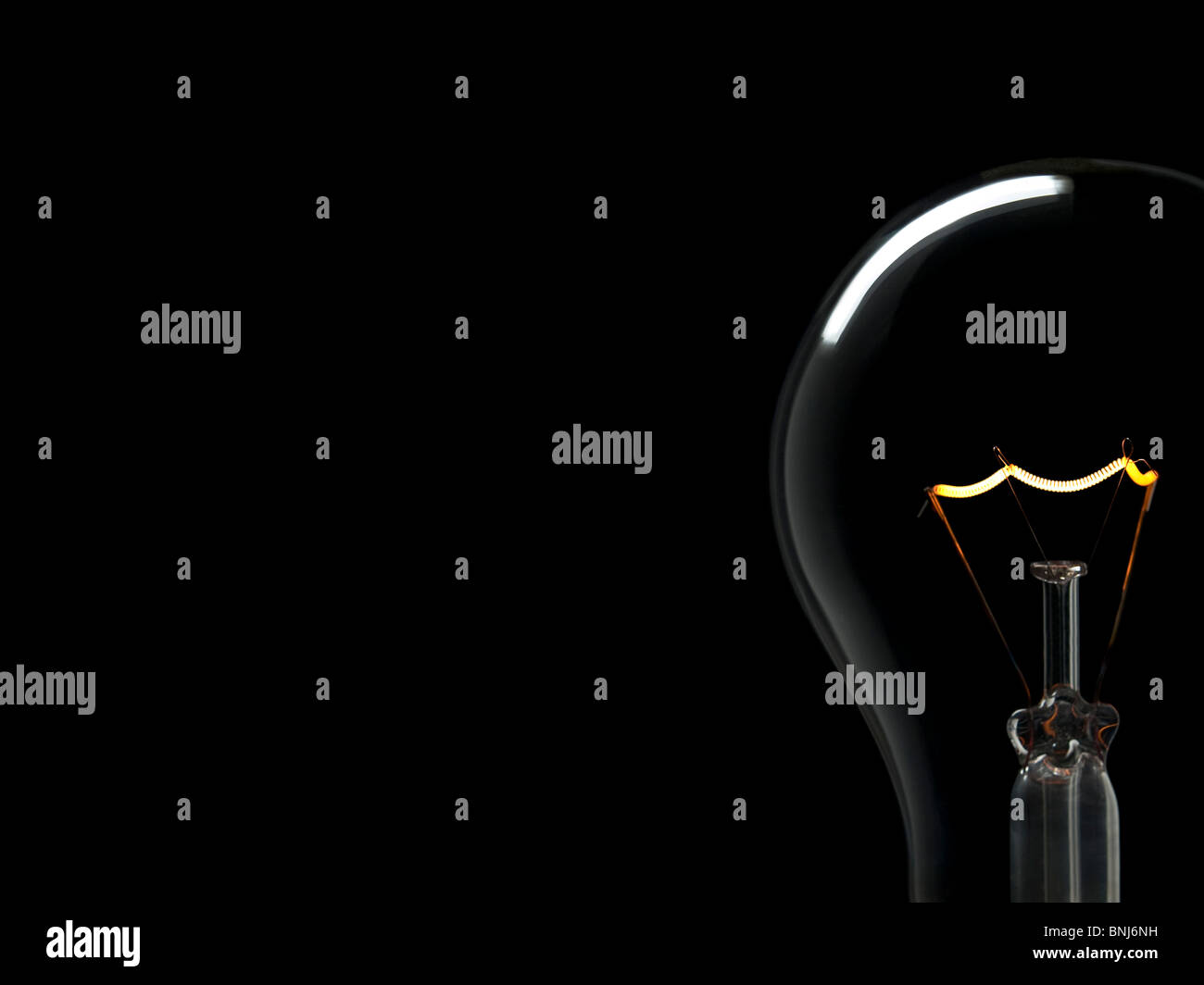 Un bulbo di luce su uno sfondo nero. Tungsteno filamento incandescente. Copia dello spazio. Foto Stock