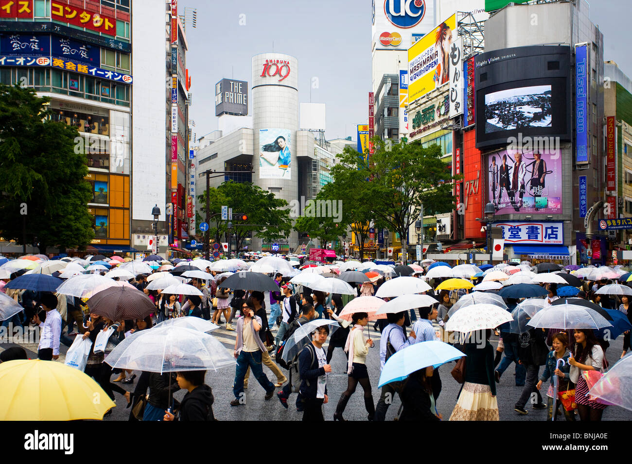 Asia Giappone Tokyo città quartiere Shibuya Passante schermate pedonale piogge ombrelloni annuncio assunzione luci al neon Foto Stock