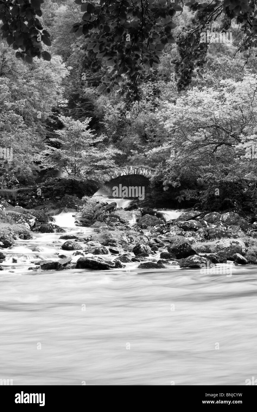 Ponte di pietra sul veloce che scorre il fiume Foto Stock