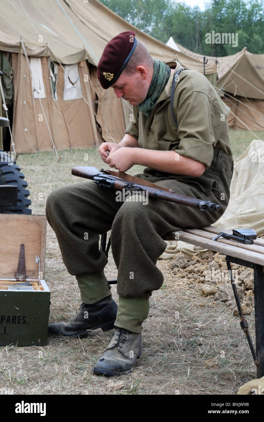 Un re-enactor raffigura una guerra mondiale 2 soldato britannico pulendo il suo Lee Enfield rifle Foto Stock