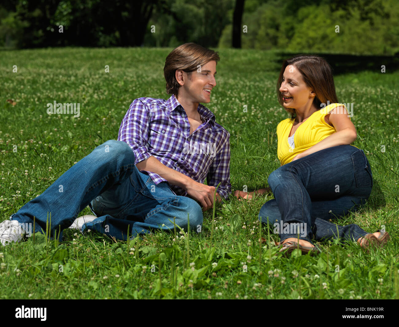 Giovane coppia felice nei loro primi anni trenta giacente su erba in un parco Foto Stock