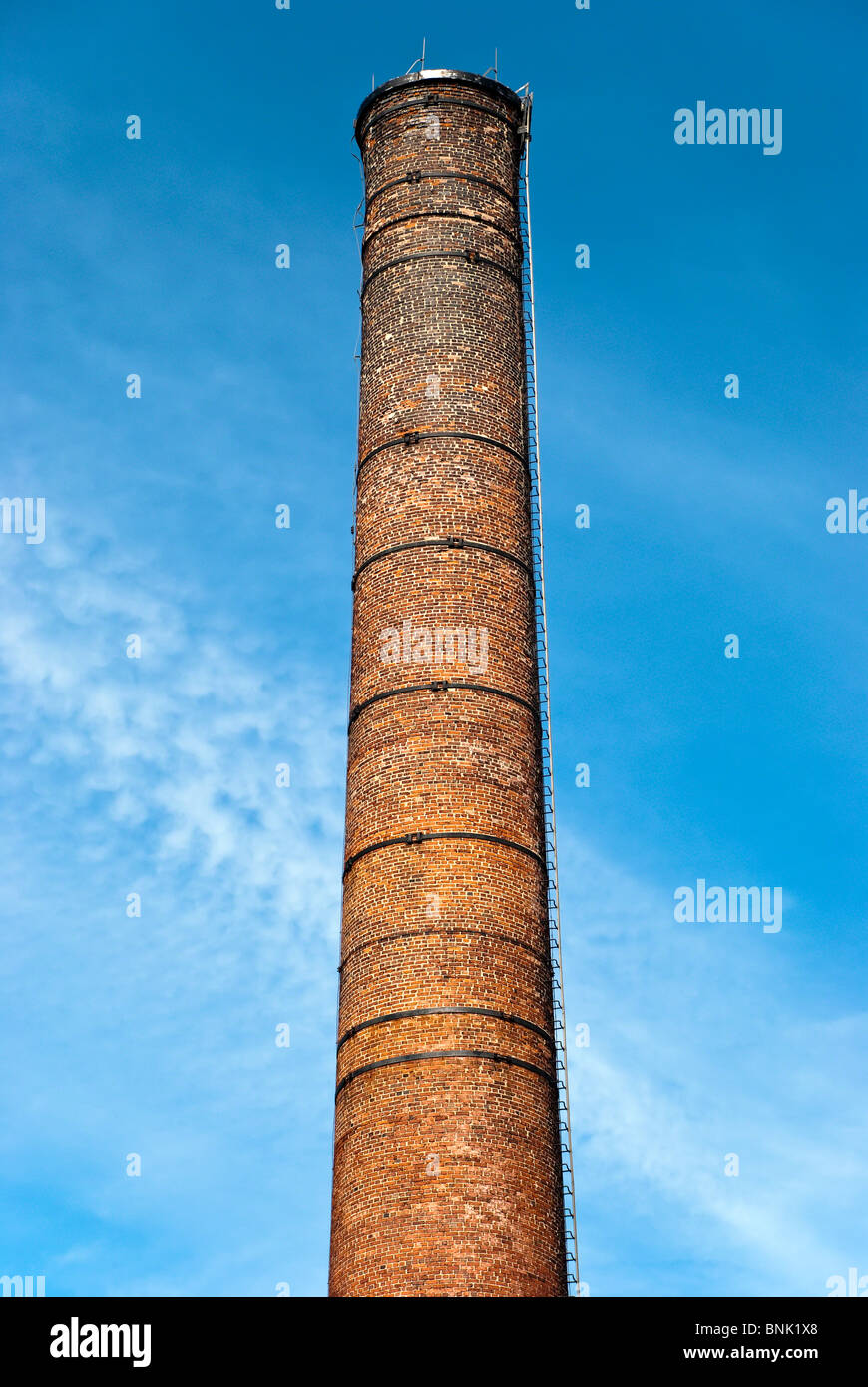 Defunta industriale ciminiera in mattoni contro il luminoso cielo blu Foto Stock