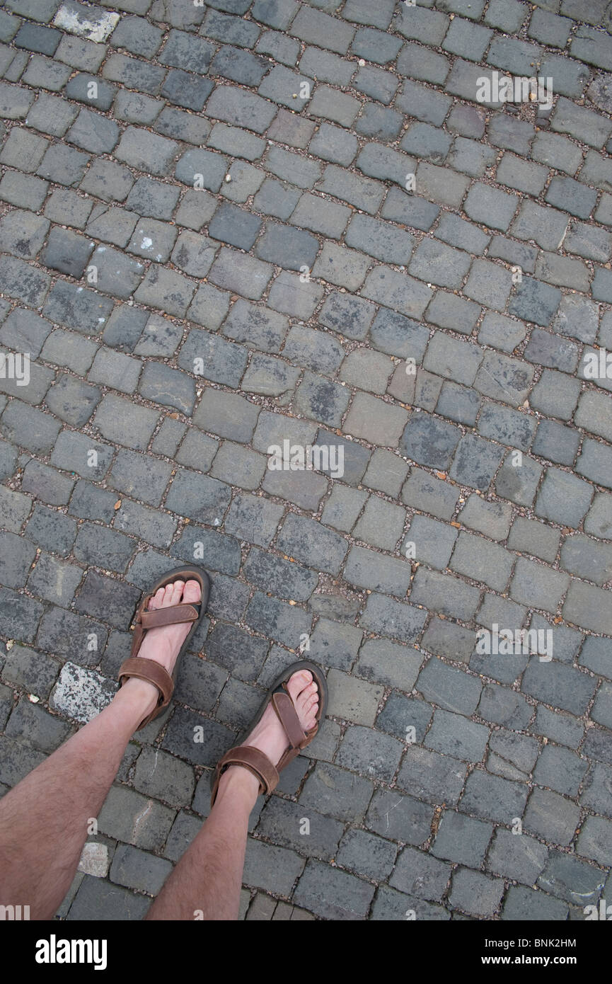 Piedi in sandali su una strada basolata Foto Stock
