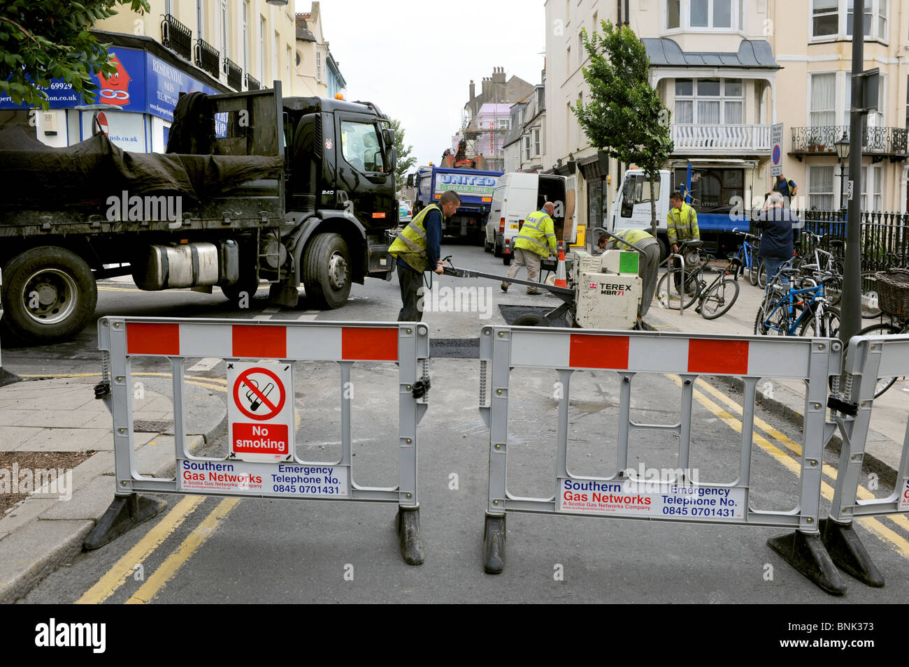 Operai che stabilisce la tarmac riparazioni di strada nel centro città di Brighton Regno Unito Foto Stock