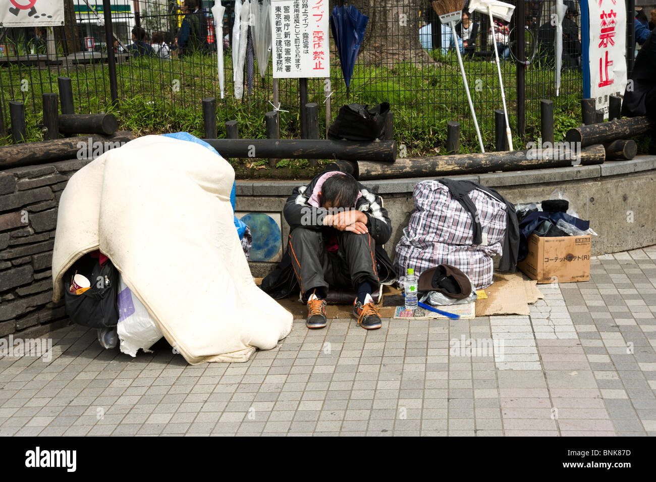 Senzatetto uomo dorme in modo irregolare a Shinjuku, Tokyo, Giappone Foto Stock