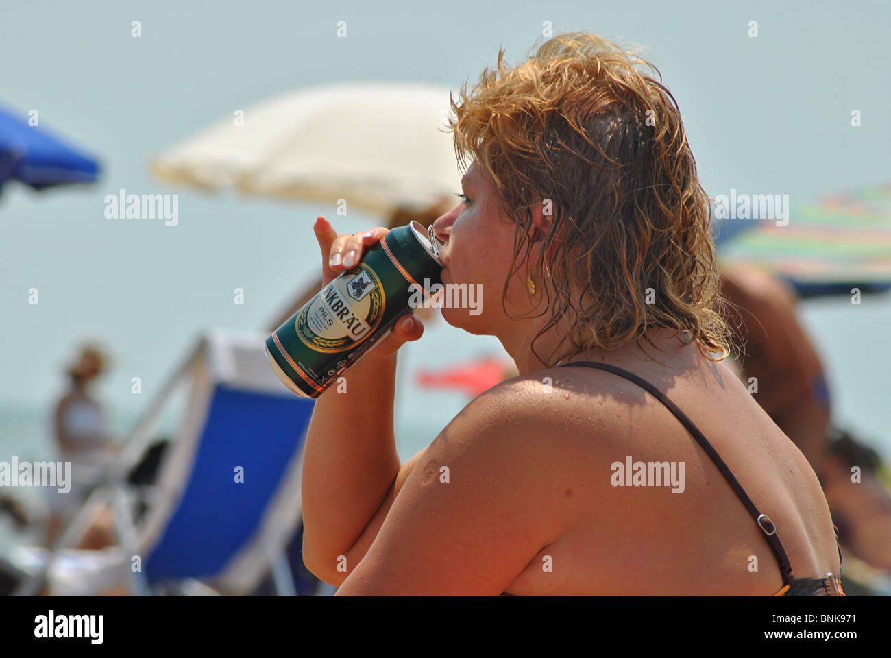 Donna obesa bere birra sulla spiaggia a Lido, Italia Foto Stock
