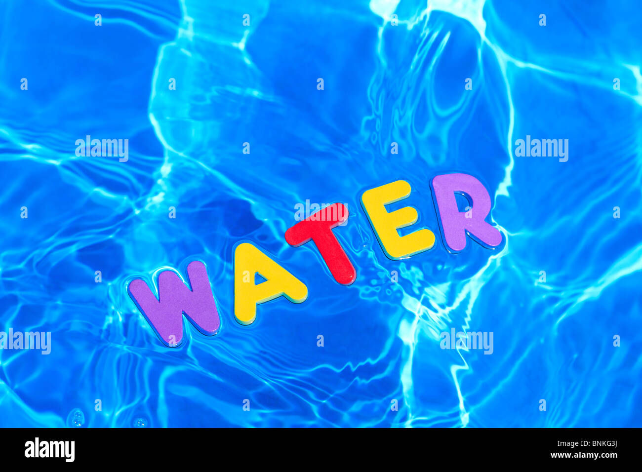La parola acqua realizzata dalla schiuma lettere galleggianti sulla superficie dell'acqua di piscina Foto Stock