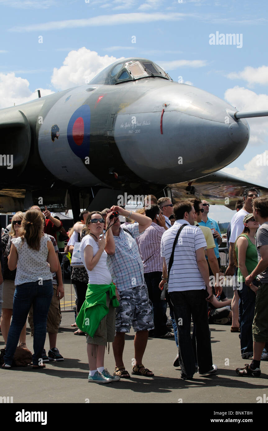 I visitatori al salone di Farnborough in piedi al di sotto di una storica bombardiere Vulcan aerei per guardare il display di volo Foto Stock