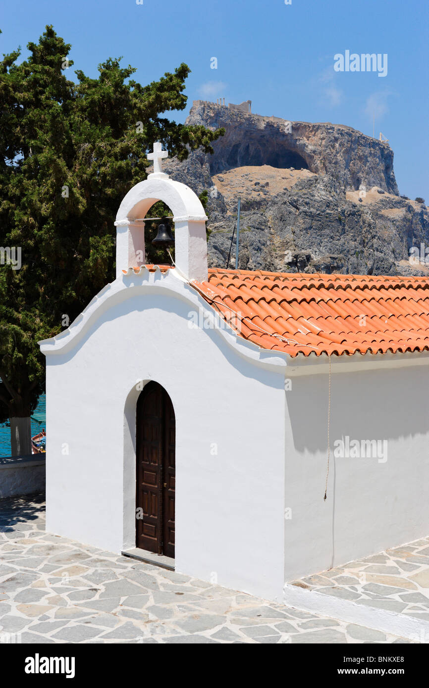 La cappella dipinta di bianco a St Paul Bay con l'acropoli dietro, Lindos, Rodi, Grecia Foto Stock