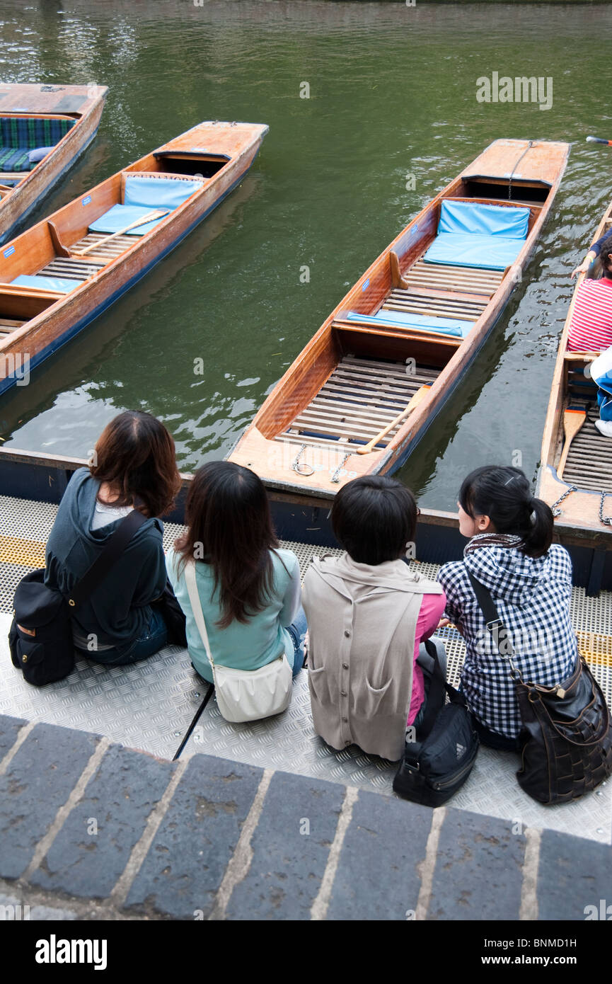 I turisti giapponesi seduti sulla banchina in attesa di andare punting sul fiume Cam, Cambridge Foto Stock